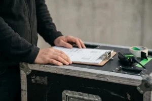 Manos cargando cajas de material técnico y trípodes para un rodaje