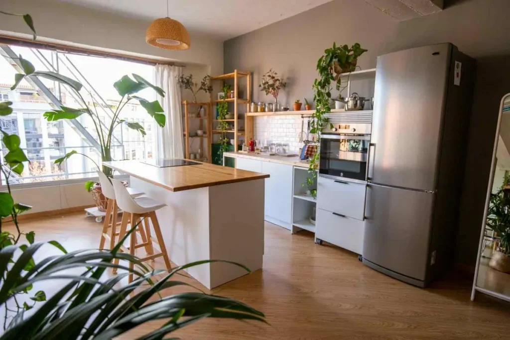 Cocina del Urban Studio con isla de madera, taburetes blancos y luz natural